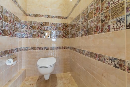 Toilet bowl in the toilet room. Restroom with brown tile decoration