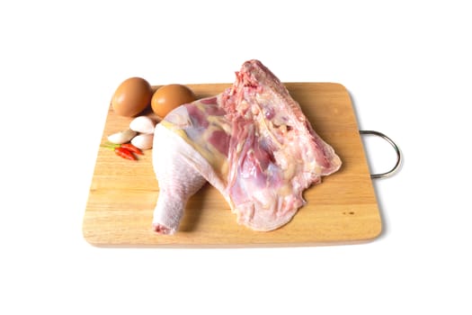 Fresh whole raw chicken with eggs, garlic and pepper on wooden chopping board isolated on white background.