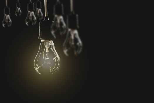 Hanging light bulbs with glowing one on dark background. Idea and creativity concept with light bulbs.