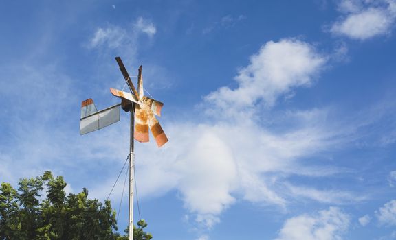 Old rusty wind turbine under the blue sky. Old windmill over blue sky.