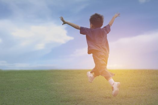 Kid running and playing have fun and joy at the grass field under the blue sky.