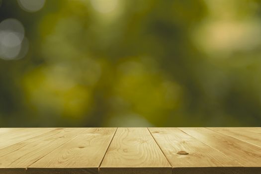 Empty wooden table with blurred green natural abstract background.