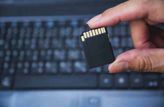 Photographer's hand holding memory card for preparing plug-in to computer.