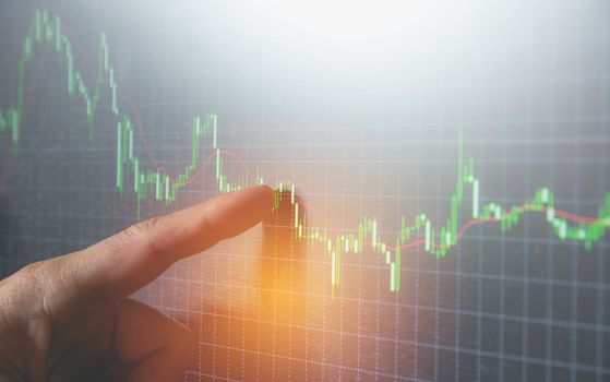 businessman point finger at indicator graph and volume bar for analysis stock market on monitor background. business finance concept.