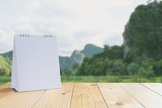 White calendar on wood table on nature background and copy space mock up.