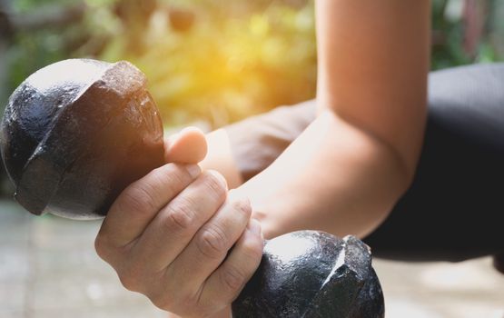 Hand of person holding dumbbell for exercise and healthy under the sunlight.
