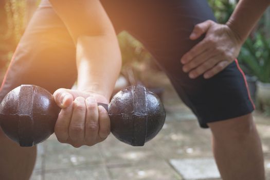 Hand of person holding dumbbell for exercise and healthy under the sunlight.