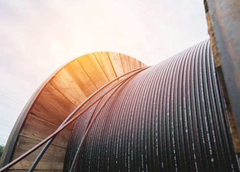 black wire  electric cable with wooden coil of electric cable under the sky.