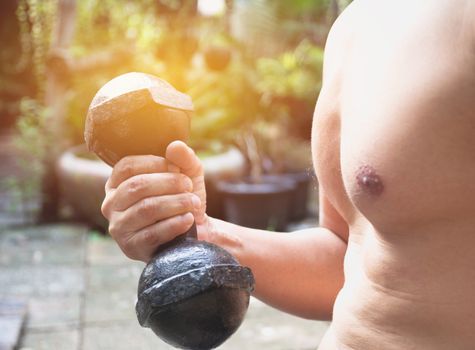 Hand of person holding dumbbell for exercise and healthy under the sunlight soft focus.