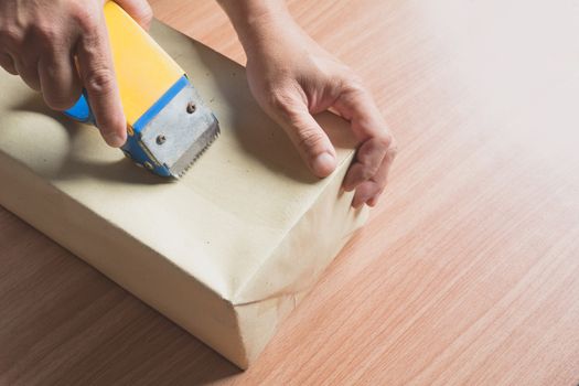 Male sealing with tape small box for moving. Close up of a hands of male holding packing machine and sealing boxes.