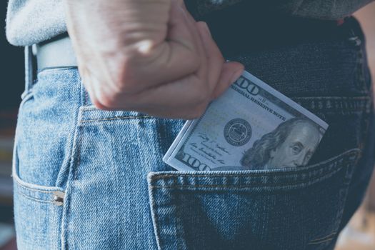 Close-up woman standing and holding money banknote from wallet pocket of jean.