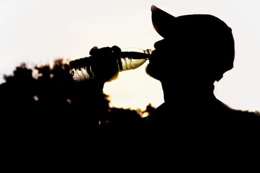 Close up of a man drinking water from a bottle after exercise. Portrait of a man drinking a water outside.