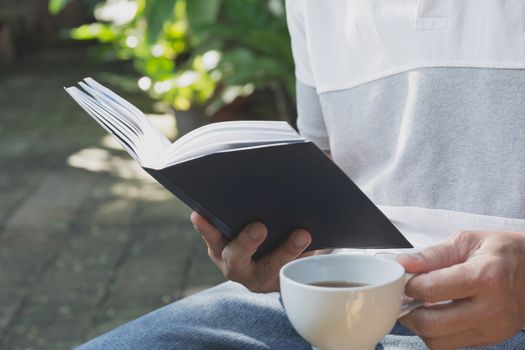 Portrait man wearing T-shirt .Man stay in the park for reading book and drinking coffee.