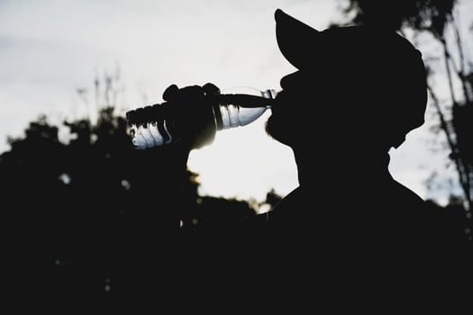 Close up of a man drinking water from a bottle after exercise. Portrait of a man drinking a water outside.