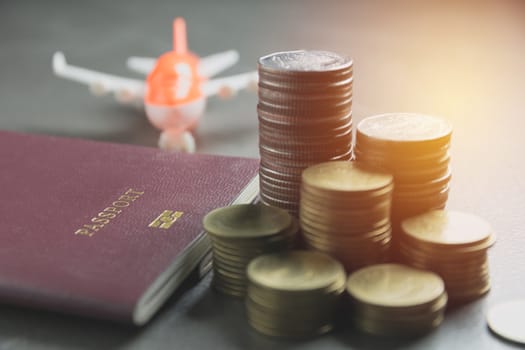 Closeup stack coin with passport and air plane model. Financial and saving concept.