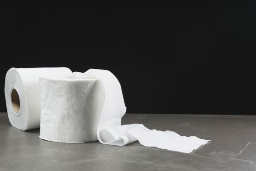 Close-up image of toilet papers roll on the table with dark background.