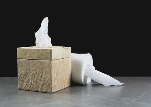 Close-up image of toilet papers roll with box on the table with dark background.