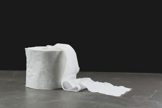 Close-up image one of toilet papers roll on the table with dark background.