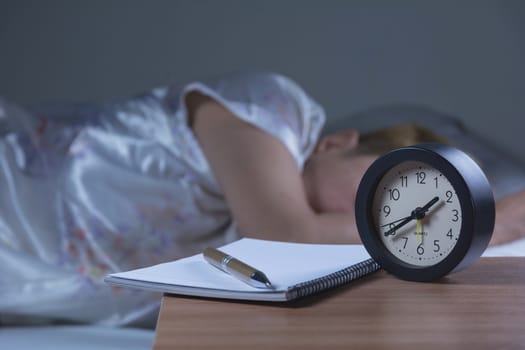 woman sleeping in her bed at night, she is resting with alarm clock.