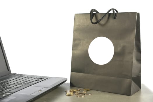 paper shopping bag with coins and computer, laptop on table isolated on white background.