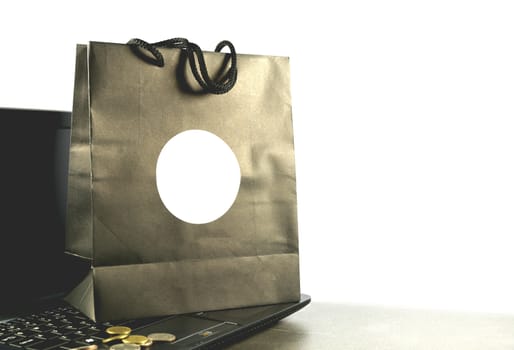 paper shopping bag with coins and computer, laptop on table isolated on white background.