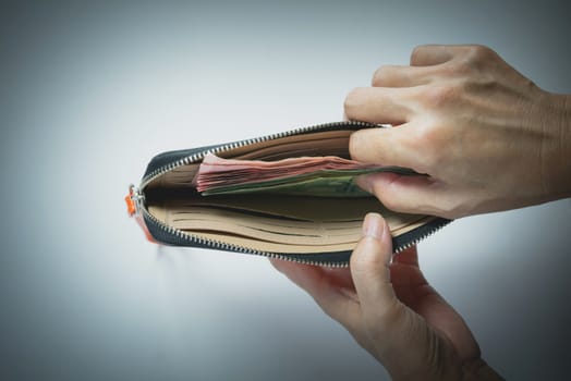 Hand holding banknote in wallet in his hand for financial and saving money concept.