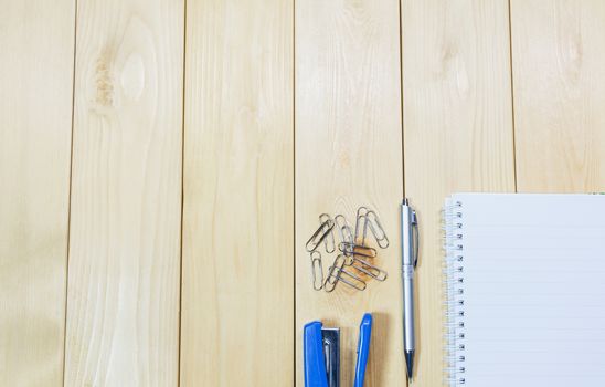 Top view of open book. Book, open with stapler and pen on wooden table background