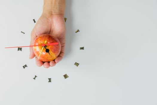 Hand holding apple with number of clock, apple shape clock on white background with copy space. 