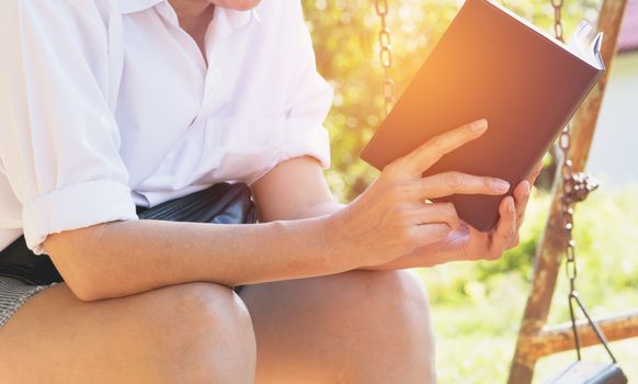 woman reading a book enjoys of rest. Woman hand holding a book for read. Concepts of rest and comfort.