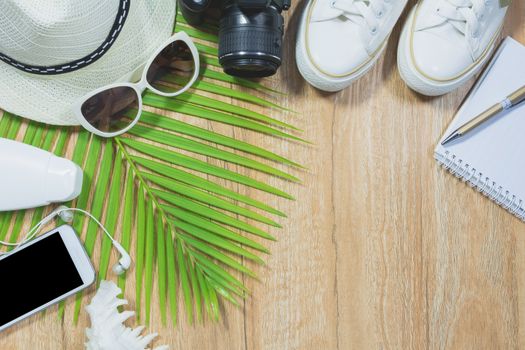 Top view of travel stuff. Essential travel items. shoes, smart phone, camera, notebook, sun glasses on wooden table background.