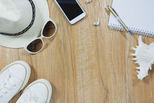 Top view of travel stuff. Essential travel items. shoes, smart phone, notebook, sun glasses on wooden table background.