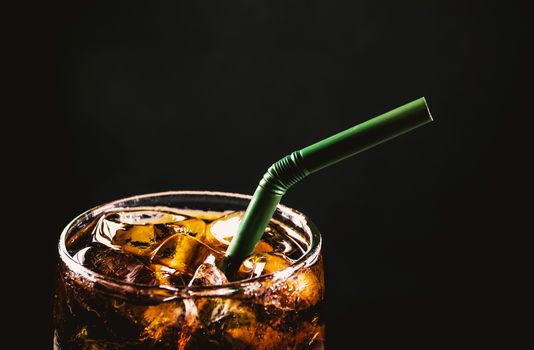 Close up iced cola glass. Sparkling water soft drinks in glass with ice on dark background.