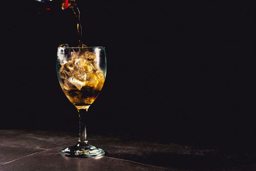 Close up iced cola glass. Sparkling water soft drinks in glass with ice on dark background.