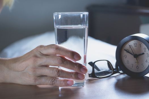 hand holding a glass of pure water. Hand holding a glass of water on table.
