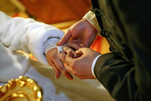 Groom putting a ring on bride 's finger during wedding ceremony