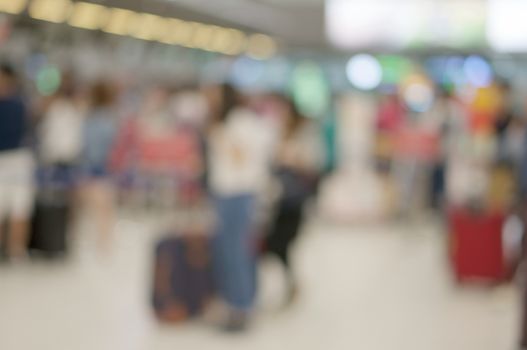 Abstract blurred tourist with luggage waiting for check in at airport terminal. Business tourism and rush concept photography.