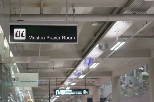 Muslim prayer room information board sign with white character on black background at international airport terminal.