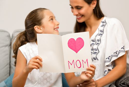 Mother receiving a greeting card on mother's day from her daughter