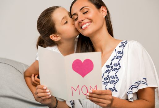 Mother receiving a greeting card on mother's day from her daughter