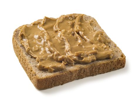 Photo of a slice of whole wheat bread covered in peanut butter. Isolated on white with clipping path included.