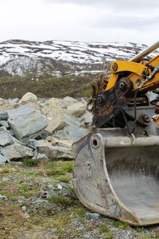 Excavator bucket moving stones in mountains close-up