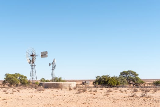 A farm scene with two windmills, a dam and a hut next to the C10-road between Velloorsdrif  border post and Karasburg in the southern part of Namibia