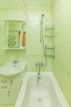 Small green tile bathroom with bath tube and sink