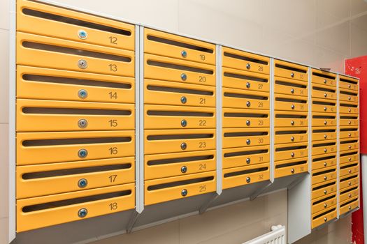 row of orange mailboxes in corridor of apartment building