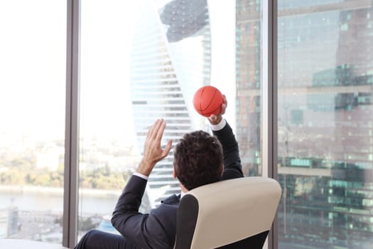 Business man playing with a basketball at the office