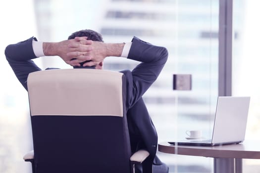 Businessman relaxes sitting in the office and looking in window