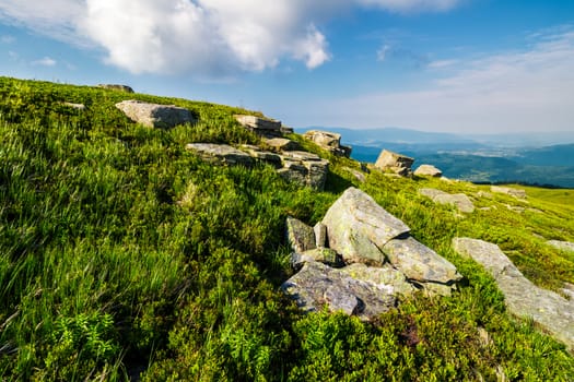 grassy hill with lots of boulders. lovely mountainous landscape. fine summer weather