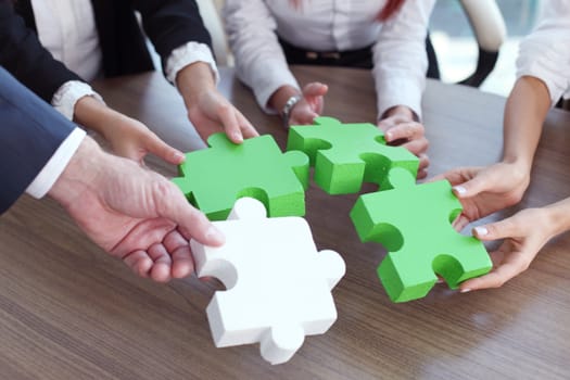 Group of business people assembling jigsaw puzzle and represent team support and help concept in office