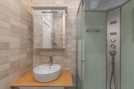 Small beige tile bathroom with Shower cabin and sink