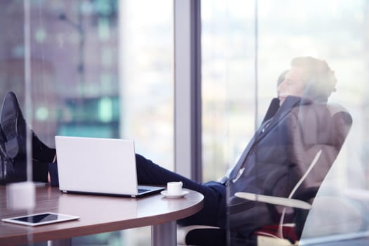 Businessman relaxes sitting in the office and looking in window